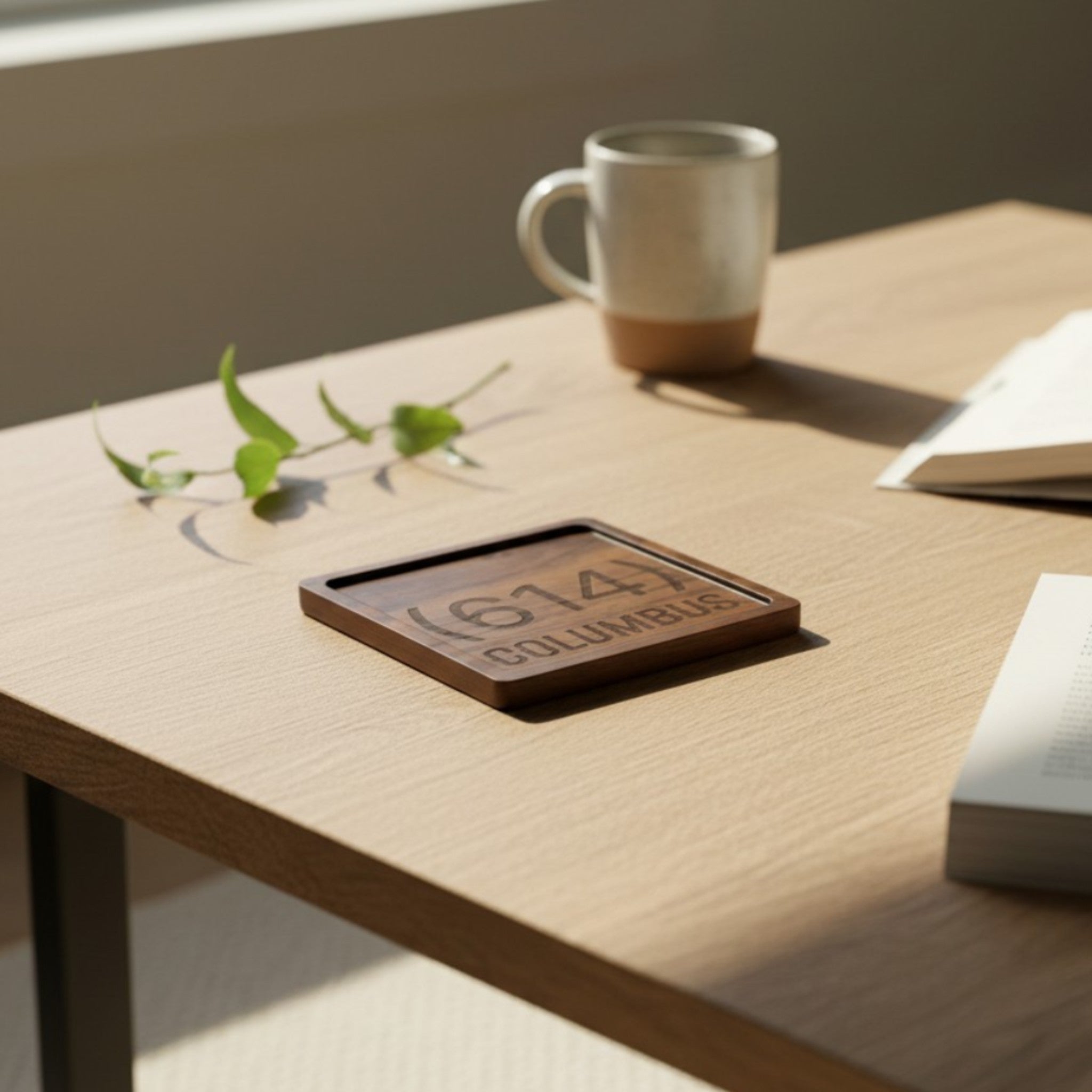 Wooden coaster made of black walnut featuring a personalized laser engraved design, sitting on a table.