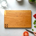 Cherry wooden cutting board with personalized engraving on a kitchen counter.