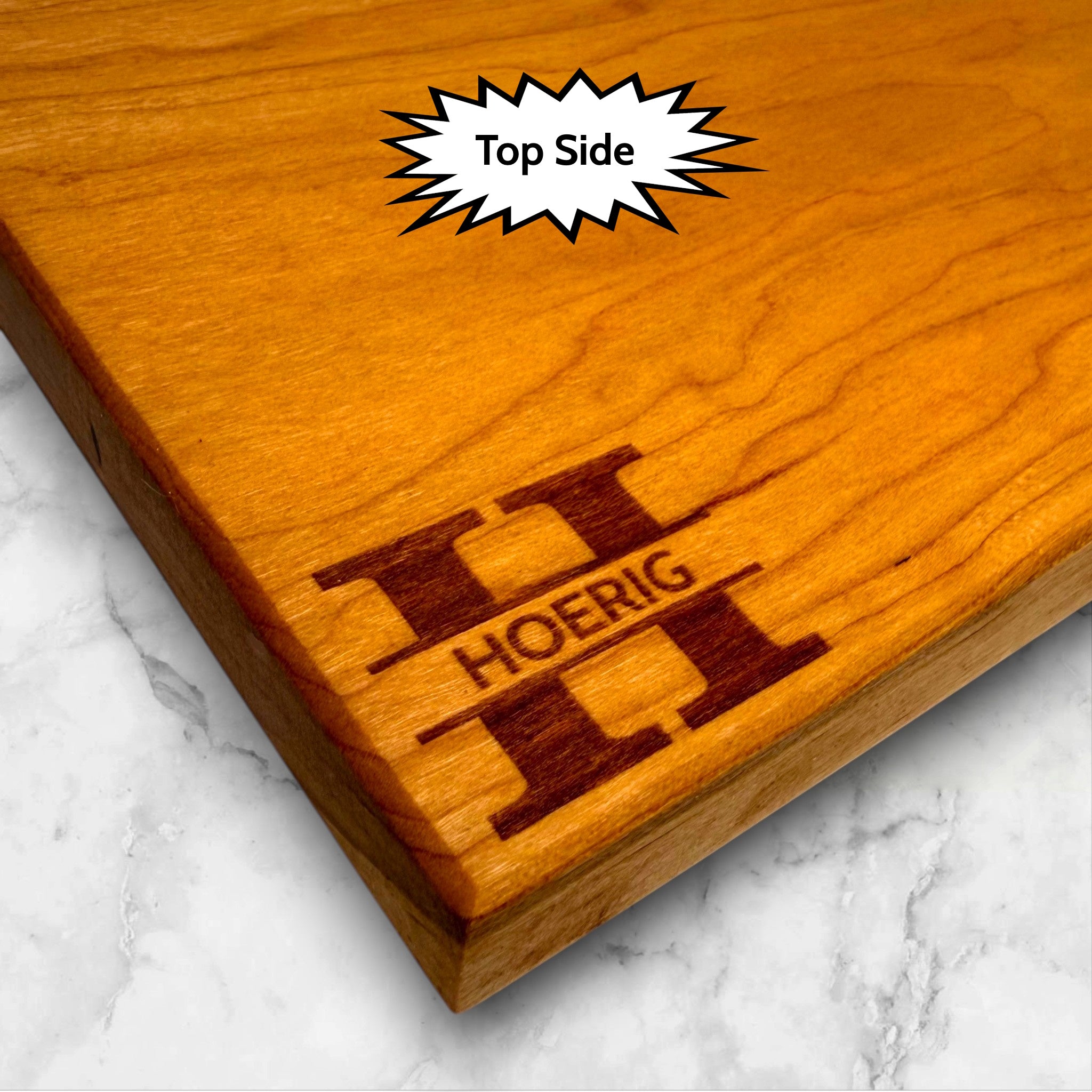 Cherry wooden cutting board with personalized engraving on a kitchen counter.