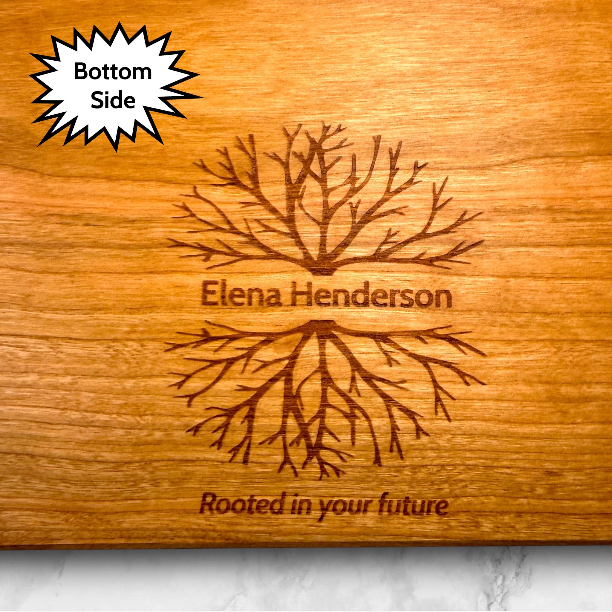 Wooden cherry cutting board with tree and root design, engraved with 'Elena Henderson' and 'Rooted in your future'.