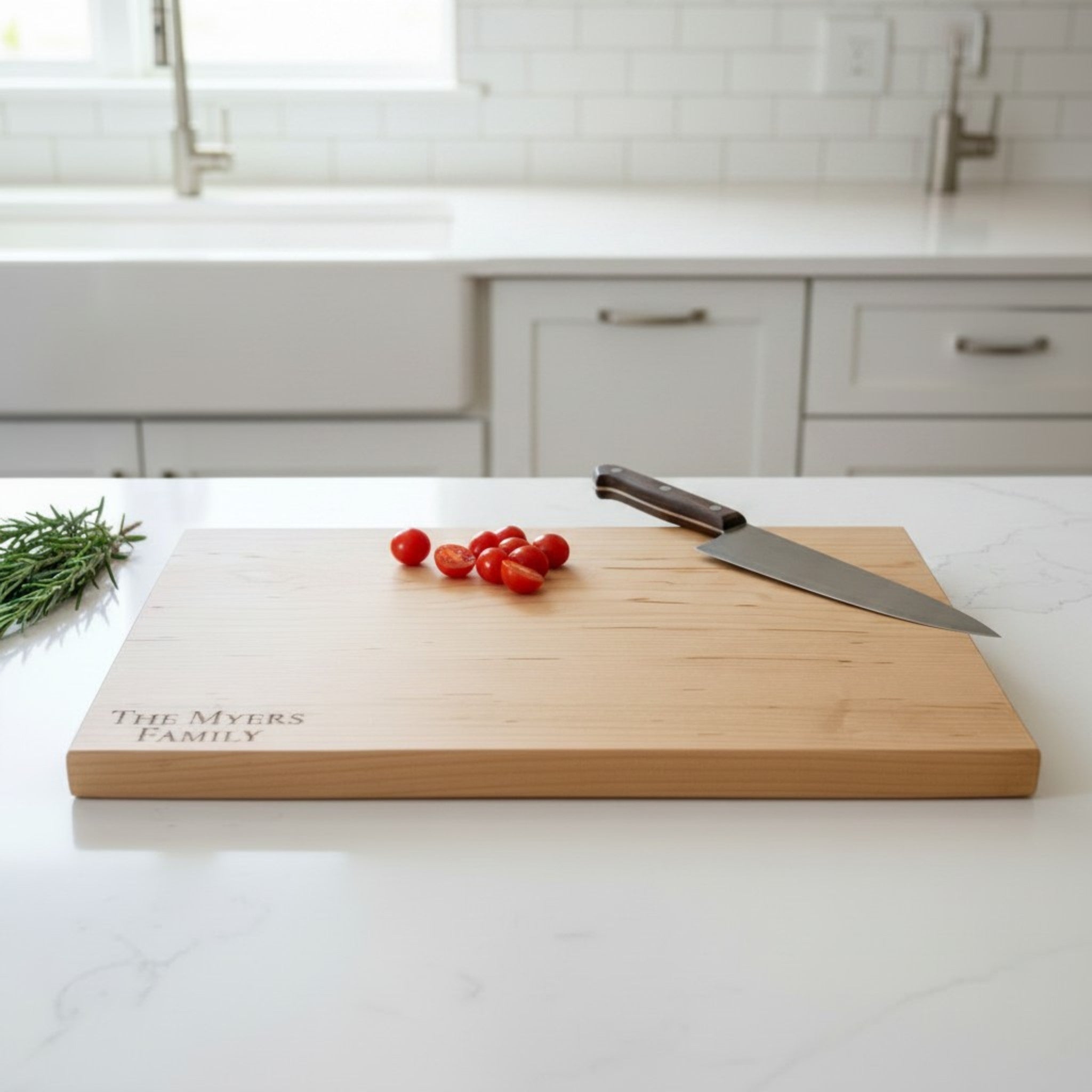 Maple wooden cutting board with personalized laser engraved design and text on a white kitchen countertop.