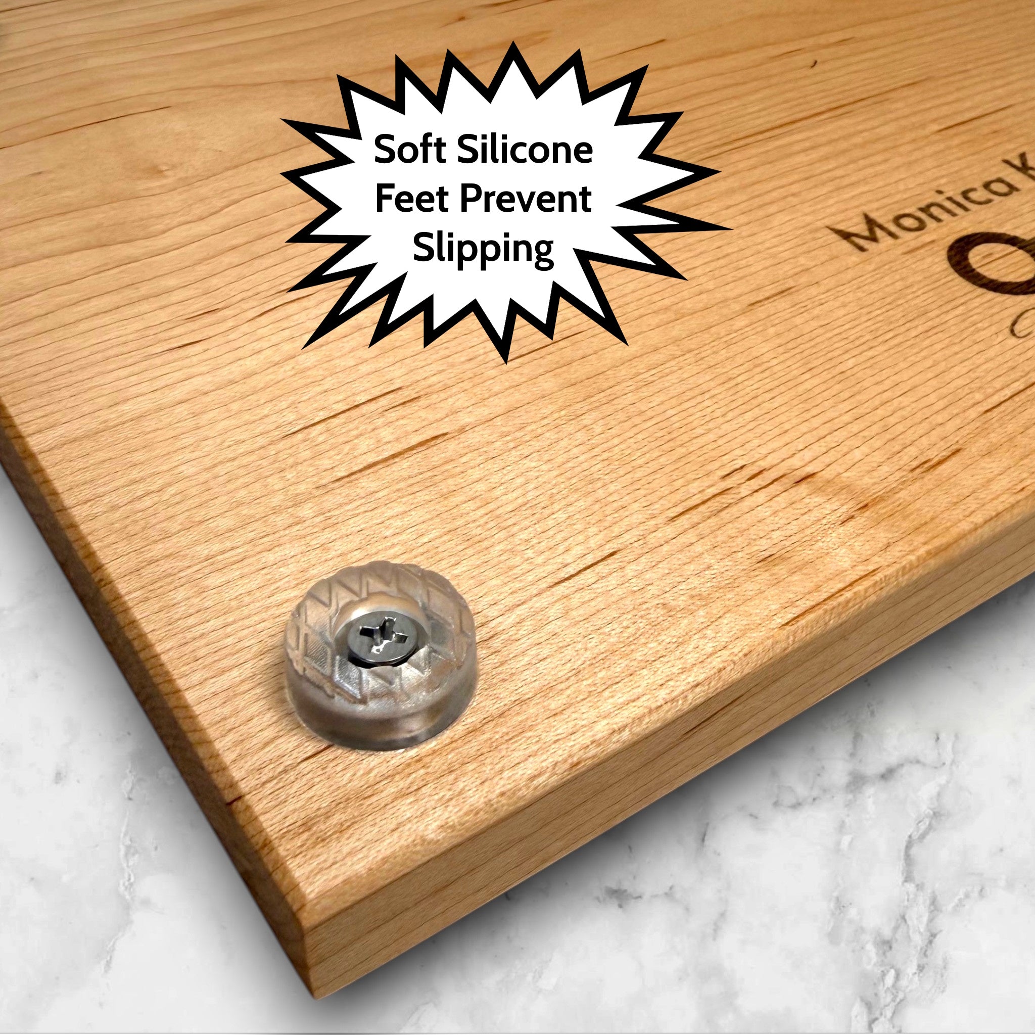 Wooden maple cutting board with soft silicone feet on a marble surface.