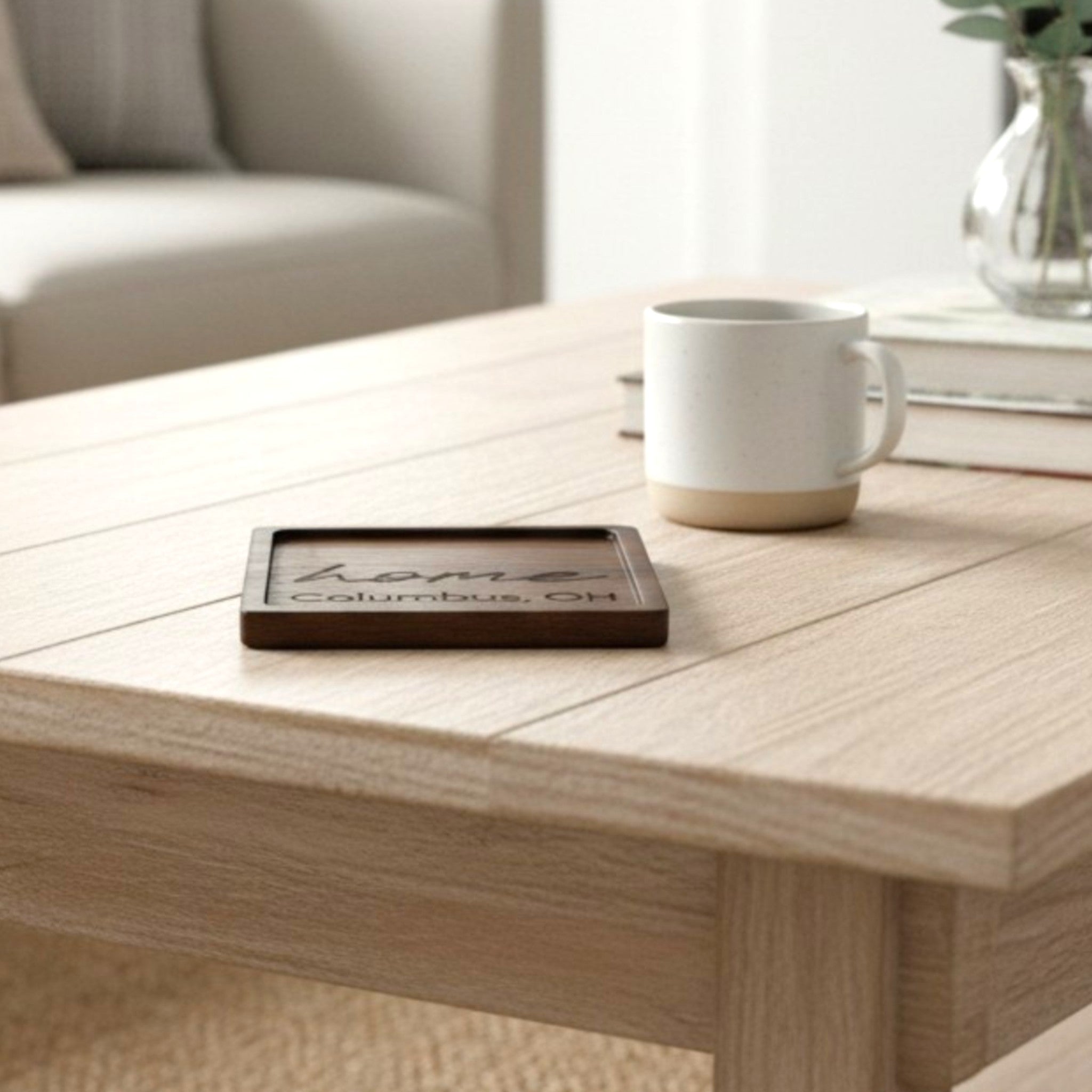 Wooden coaster made of black walnut featuring a personalized laser engraved design, sitting on a table.