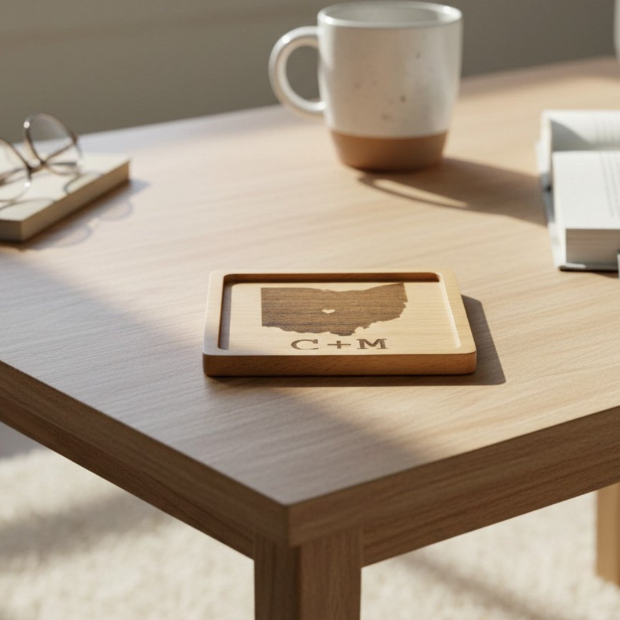 Wooden coaster made of beech featuring a personalized laser engraved design, sitting on a table.